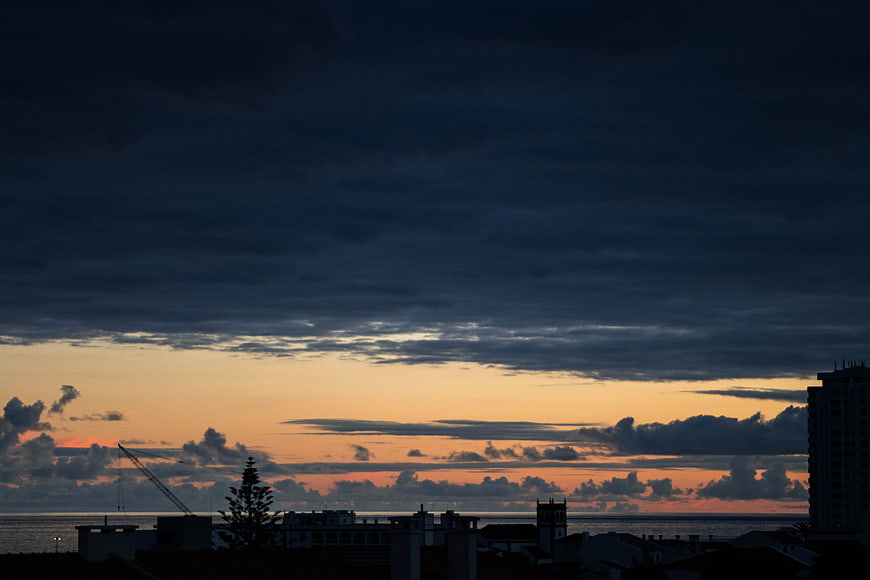 Dramatic sunset over coastal city skyline with clouds