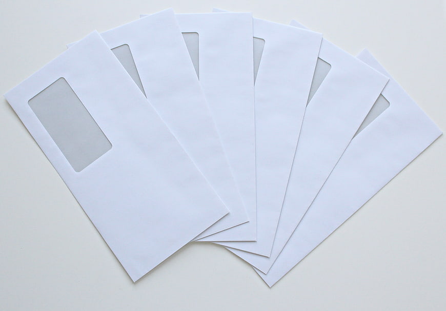 White Window Envelopes Fanned Out On Light Gray Background