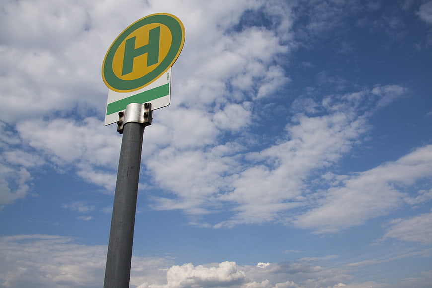 German Bus Stop Sign Against Blue Sky with Clouds