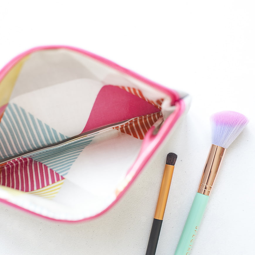 Colorful makeup pouch with brushes on white background