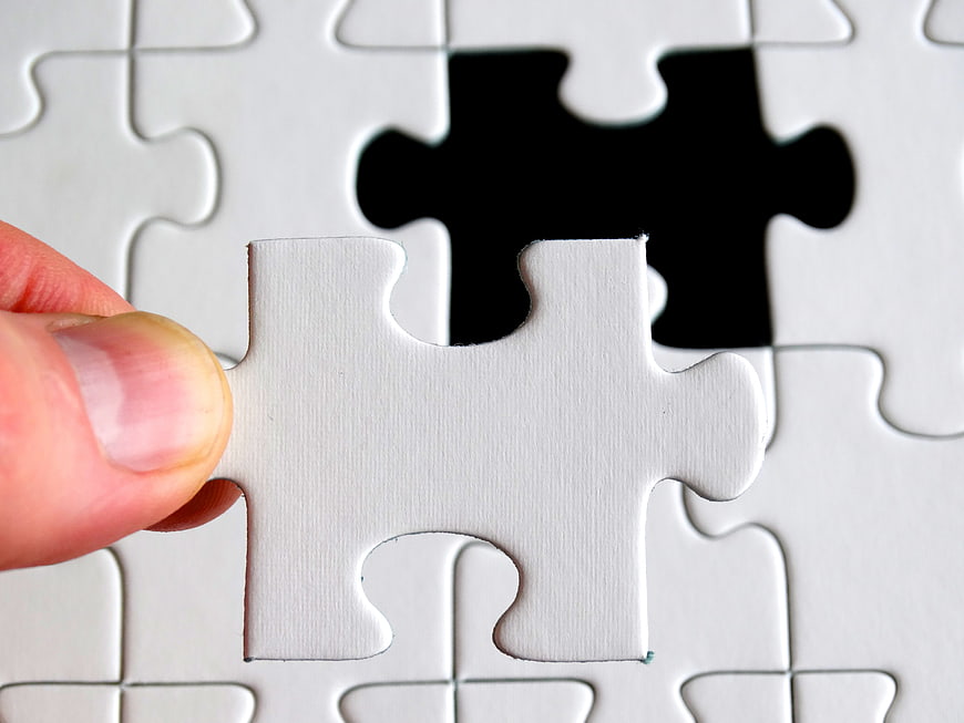 Hand Placing Last White Puzzle Piece into Missing Slot