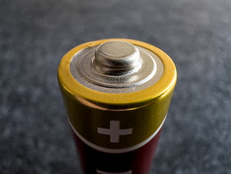 Close-up of Alkaline Battery Positive Terminal on Gray Background