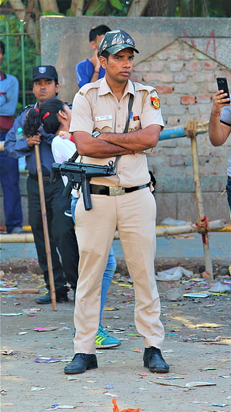 Indian police officer standing with arms crossed and rifle