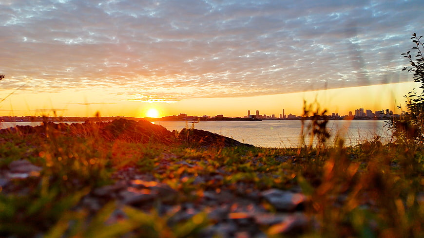 Golden Sunset Over Boston Skyline with Rocky Shoreline
