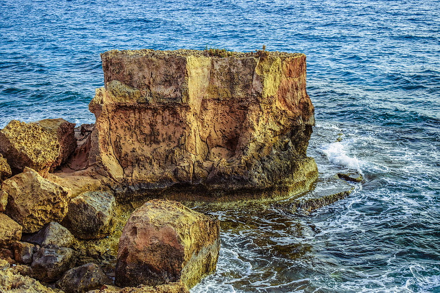 Rugged Sandstone Rock Formation in Blue Sea Water