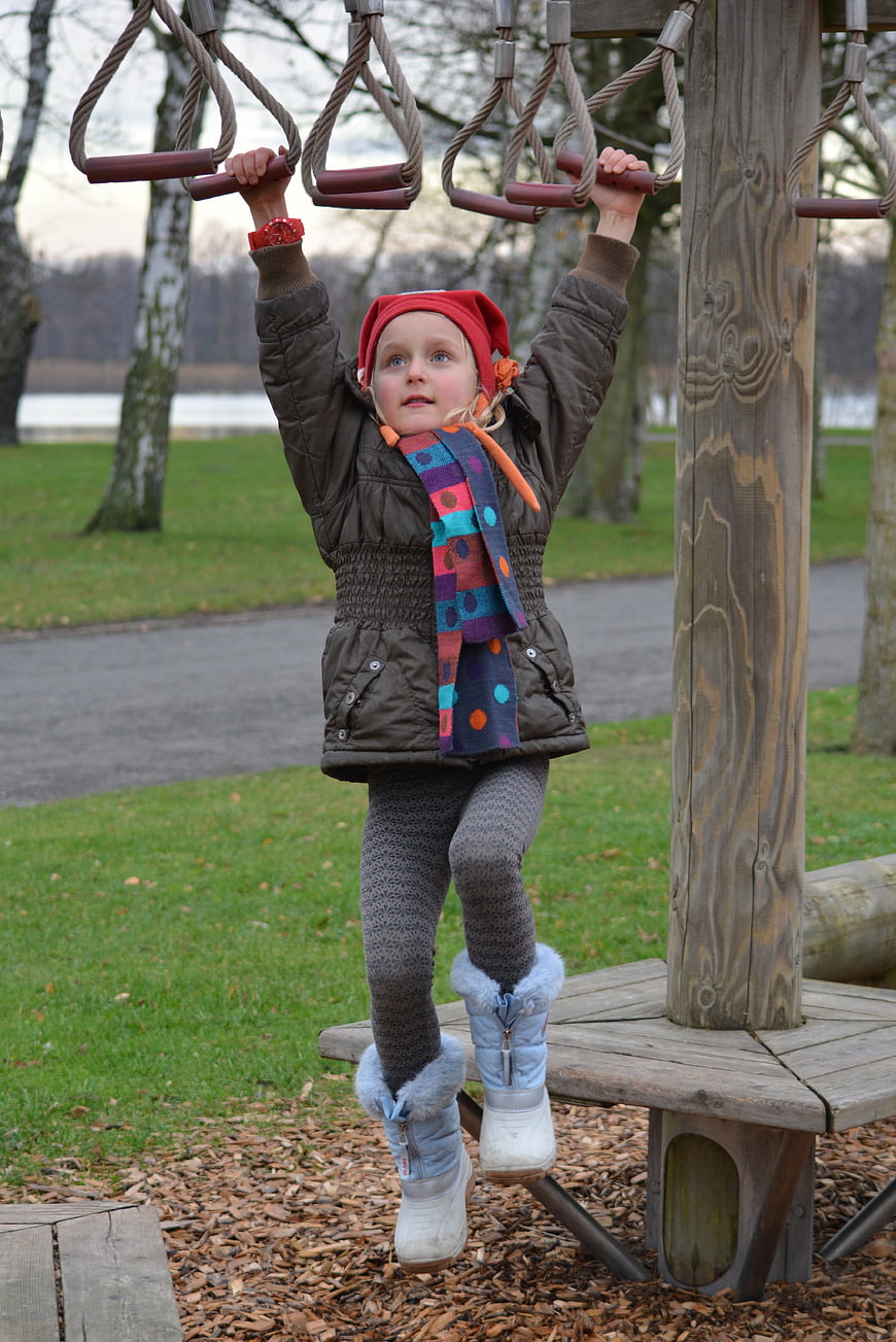 Young Girl Climbing Rope Obstacle Course In Park