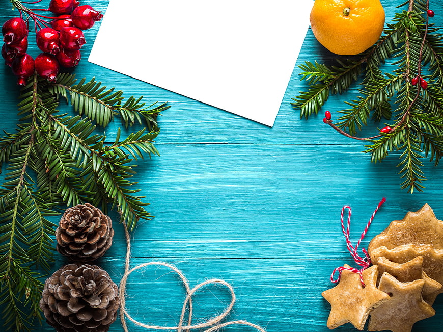 Christmas flat lay with gingerbread cookies, pine branches, and white card on blue wood