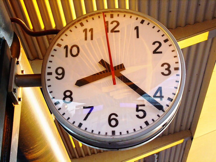 Close-up of a round analog clock on a corrugated metal wall