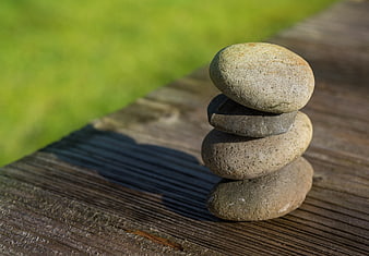 Stacked stones on wooden deck with blurred green background