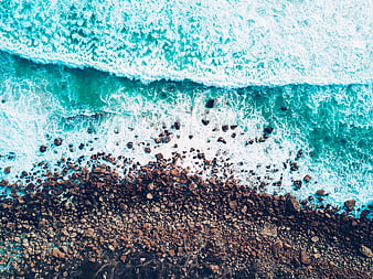 Aerial View of Turquoise Waves Crashing on Rocky Shore