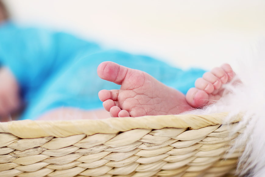 Close-up of a newborn baby's feet in a woven wicker basket