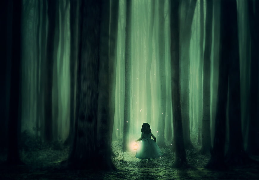 Mysterious girl with lantern in dark foggy forest