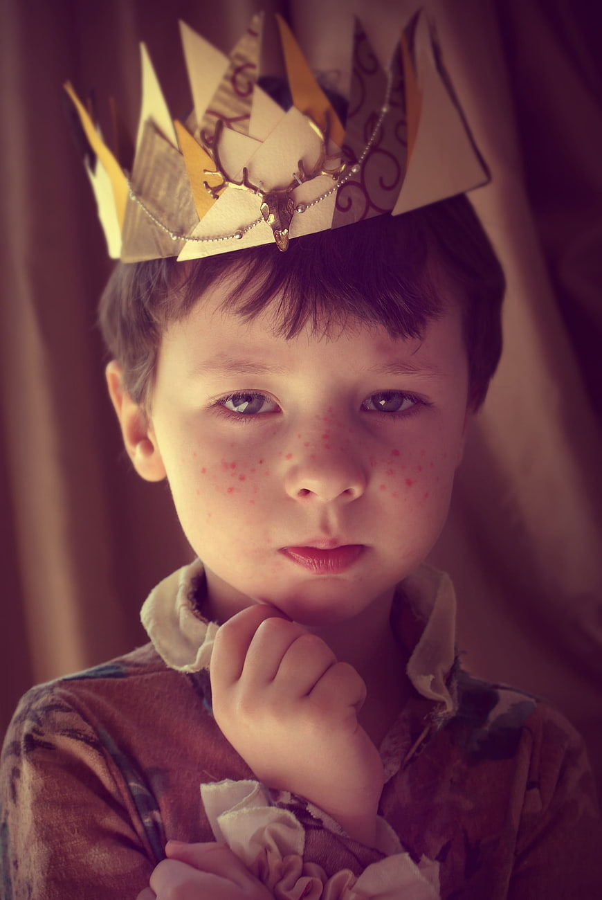 Portrait of a young boy wearing a handmade paper crown