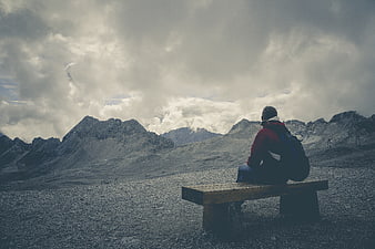 Lone Hiker Sitting on Bench Overlooking Mountain Landscape