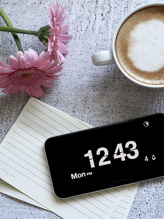 Flat lay of smartphone, coffee, and pink flowers on desk