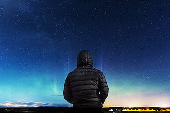 Man in Hoodie Watching Aurora Borealis Under Starry Night Sky