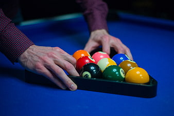 Hands Racking Billiard Balls on Blue Pool Table