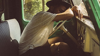 Tired man sleeping in the driver's seat of a vintage green van