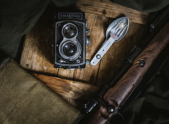 Vintage Rolleiflex Camera, Spork, and Rifle on Wooden Surface