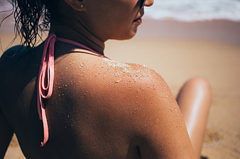 Close-up of woman with sand on shoulder at beach