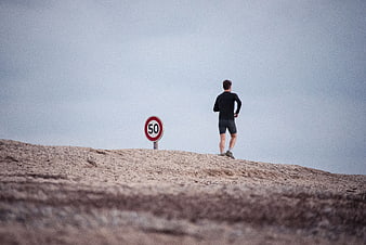 Man jogging on hill with speed limit sign