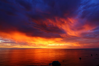 Dramatic fiery sunset over ocean with vibrant clouds