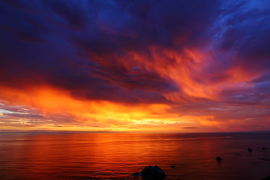 Dramatic fiery sunset over ocean with vibrant clouds