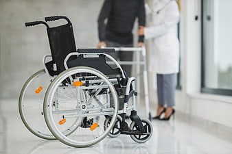 Empty wheelchair in hospital corridor with doctor and patient