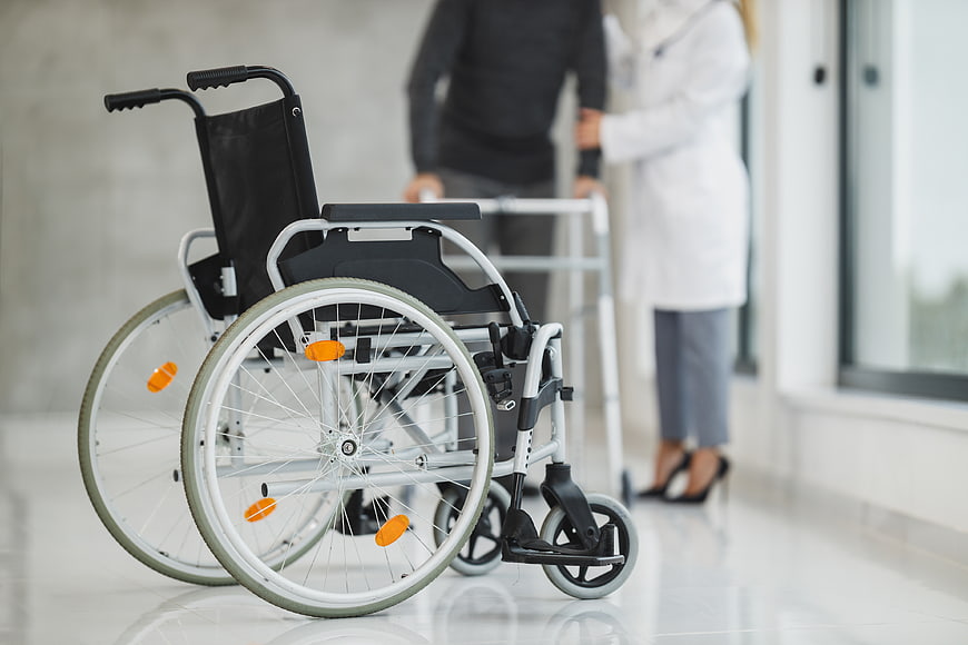 Empty wheelchair in hospital corridor with doctor and patient