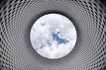 Low-angle view of modern architectural lattice tunnel against sky