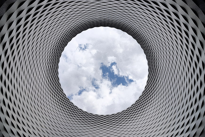 Low-angle view of modern architectural lattice tunnel against sky