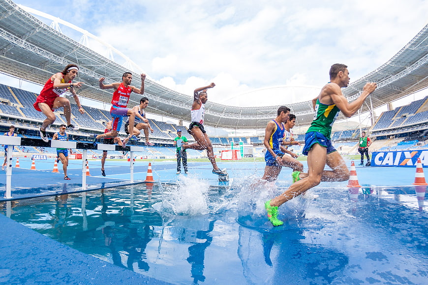 Athletes sprinting through water obstacle in stadium