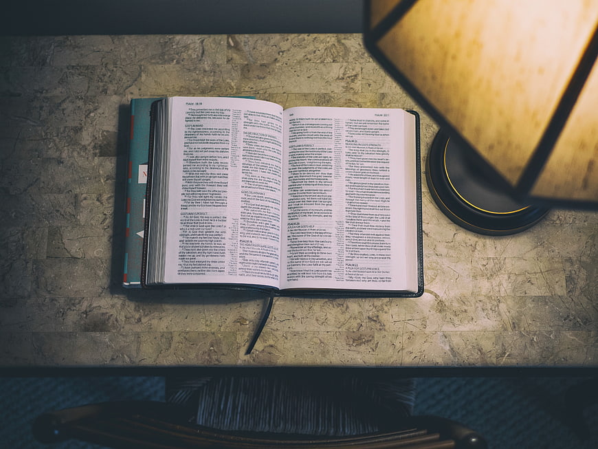 Open Bible on Desk with Warm Lamp Light