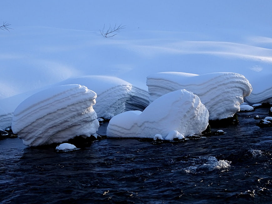 Snow-covered rocks in a flowing winter river