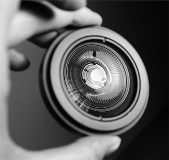 Close-up of hand holding flashlight bulb black and white
