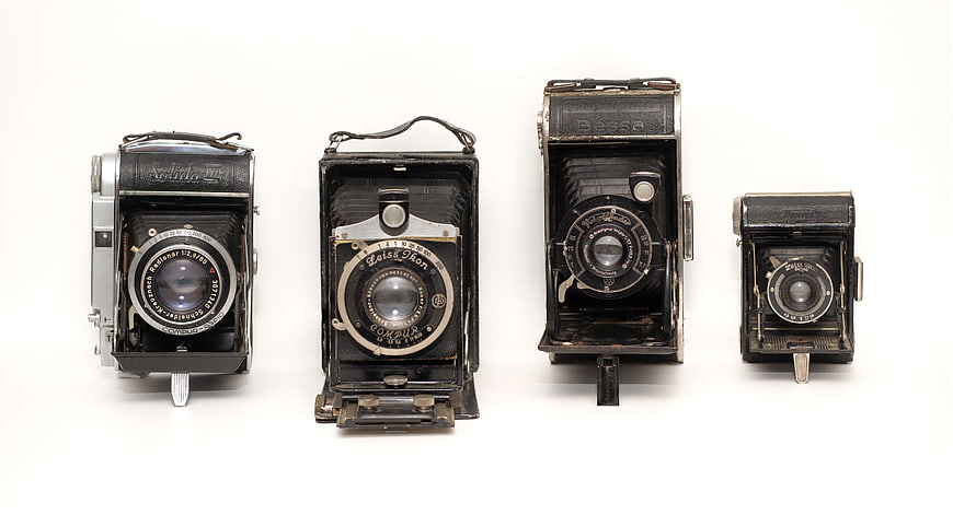 Vintage German folding cameras on white background