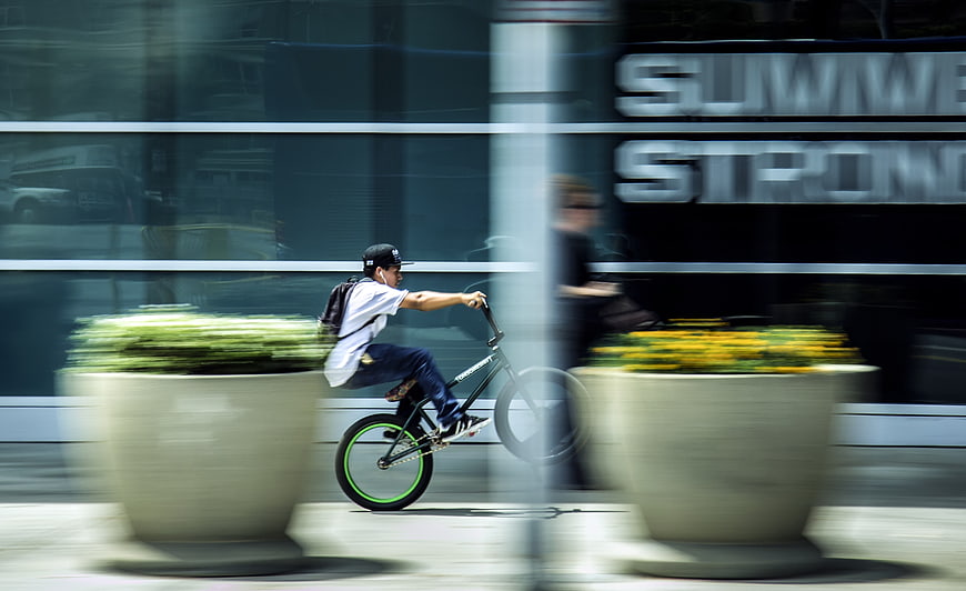 Man riding BMX bike with motion blur in urban setting