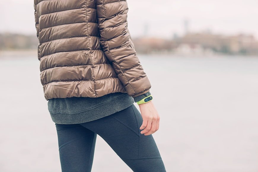 Person Wearing Brown Puffer Jacket and Fitness Tracker