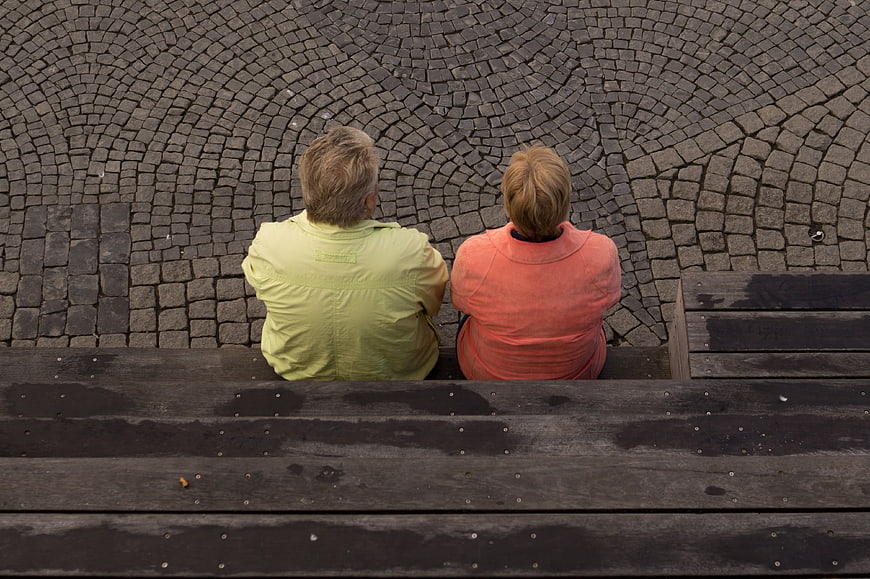 Senior couple sitting on bench overlooking cobblestone square