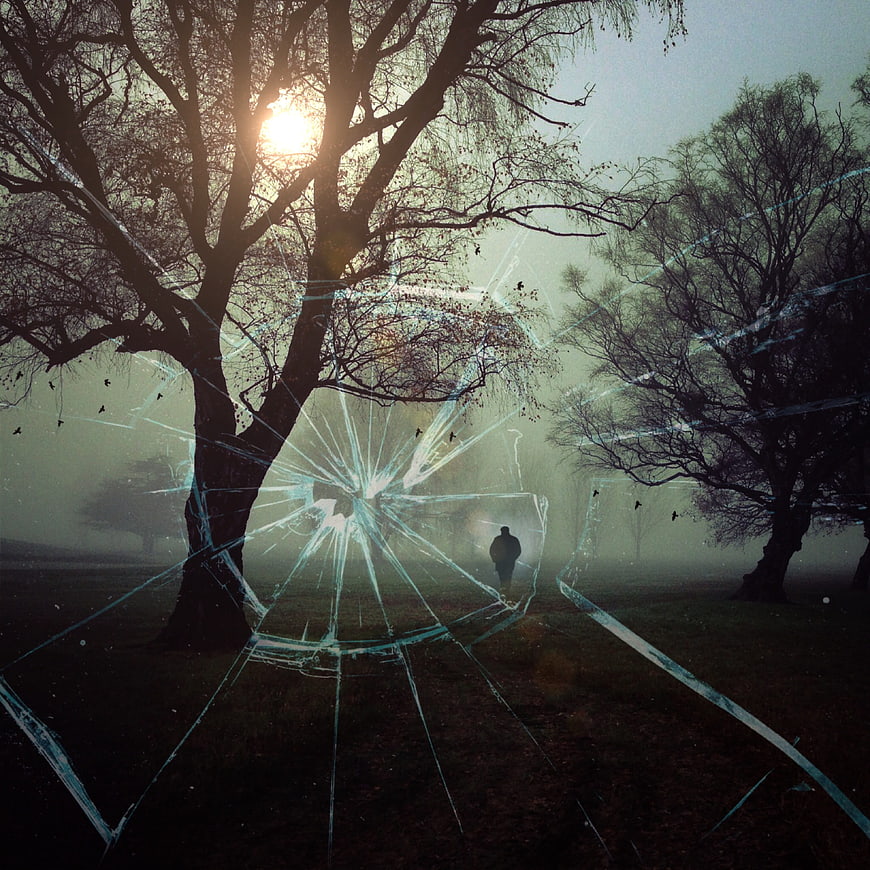 Silhouette of man walking in foggy forest with cracked glass overlay