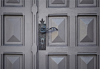 Vintage ornate metal door handle on gray wooden door