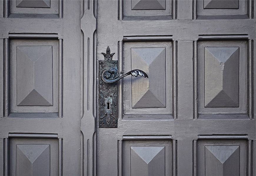 Vintage ornate metal door handle on gray wooden door