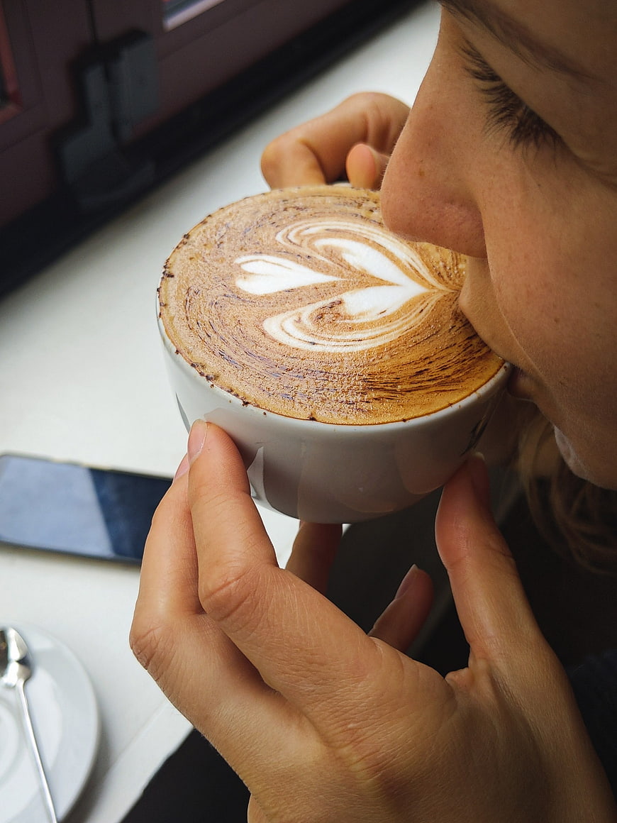 Close-up of woman sipping cappuccino with latte art