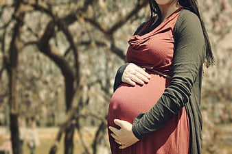 Pregnant Woman Holding Belly in Park