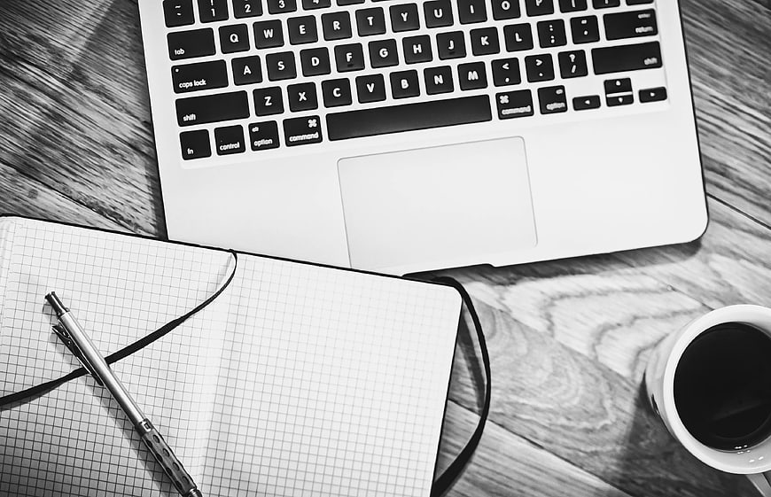 Black and White Workspace with Laptop, Notebook, and Coffee
