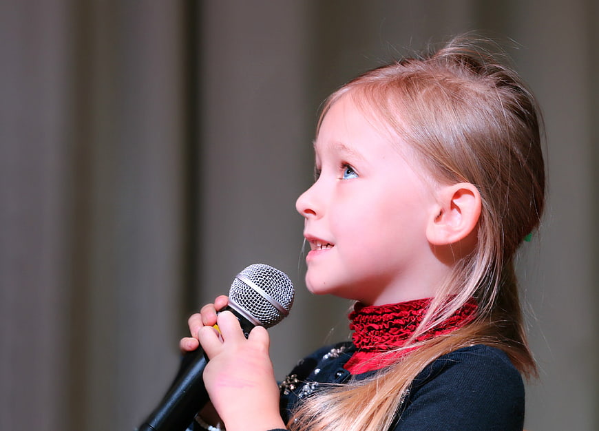 Young Girl Singing into Microphone in Profile