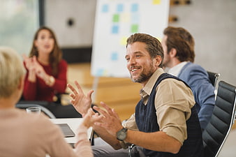 Happy businessman gesturing during office team meeting