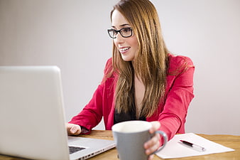 Smiling businesswoman working on laptop with coffee