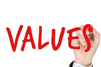 Hand writing the word values in red marker on a white background