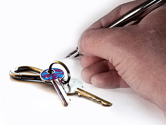 Hand signing document with keys nearby on white background